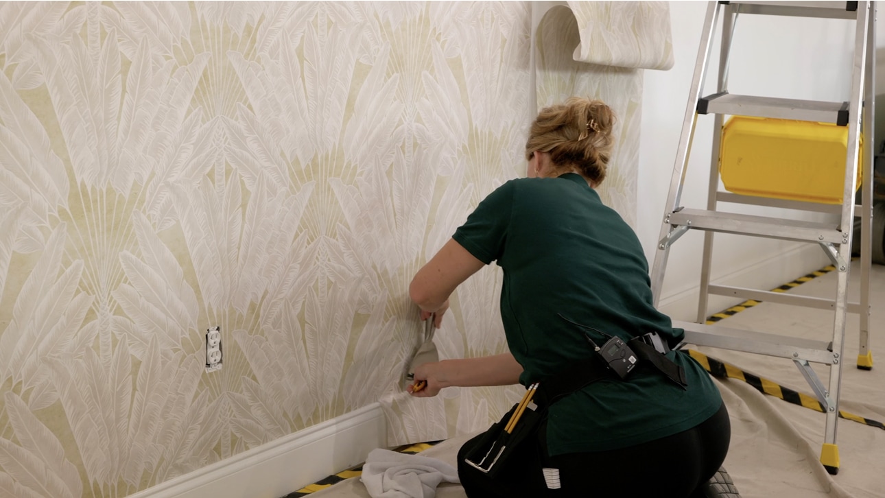 Professional installer applying patterned wallpaper to an interior wall